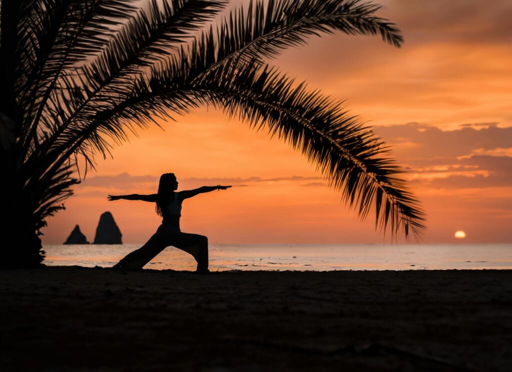Yoga at sunset under a palm tree by the sea