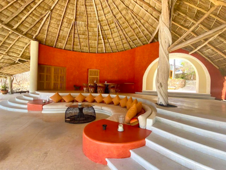 Palapa lounge with a curved coral banquette and steps to the terrace