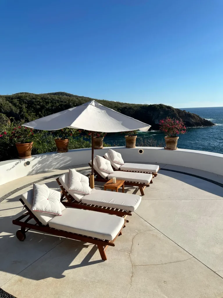 Terraza con camastros y sombrilla blanca frente al mar en Casa Papelillo
